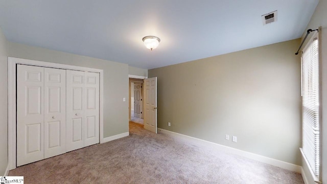 unfurnished bedroom featuring a closet and light colored carpet