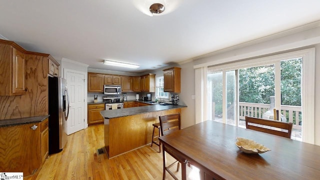 kitchen featuring ornamental molding, light hardwood / wood-style floors, a healthy amount of sunlight, and stainless steel appliances