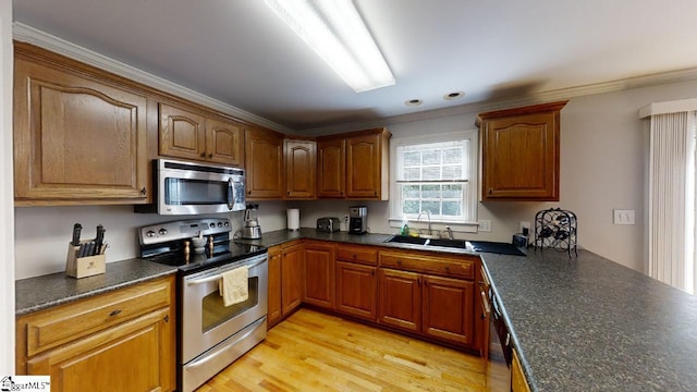 kitchen featuring ornamental molding, stainless steel appliances, light hardwood / wood-style flooring, and sink