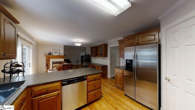 kitchen featuring crown molding, stainless steel appliances, light wood-type flooring, and dark stone counters