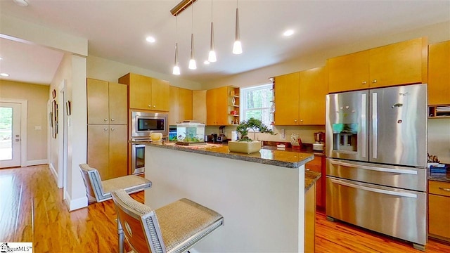 kitchen with pendant lighting, a kitchen breakfast bar, stainless steel appliances, a center island, and light wood-type flooring