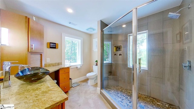 bathroom featuring vanity, a shower with door, and toilet