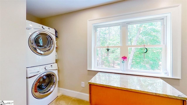 clothes washing area featuring stacked washer and clothes dryer, cabinets, a healthy amount of sunlight, and light carpet