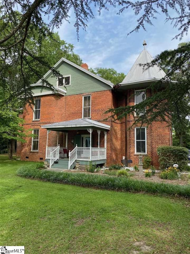 rear view of house featuring a porch and a lawn