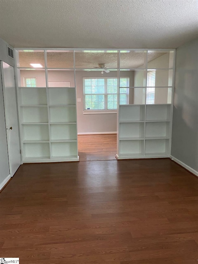 unfurnished room with ceiling fan, dark wood-type flooring, and a textured ceiling