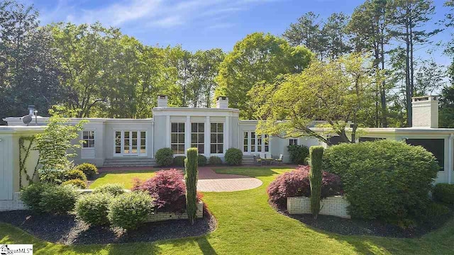 back of house with french doors and a yard