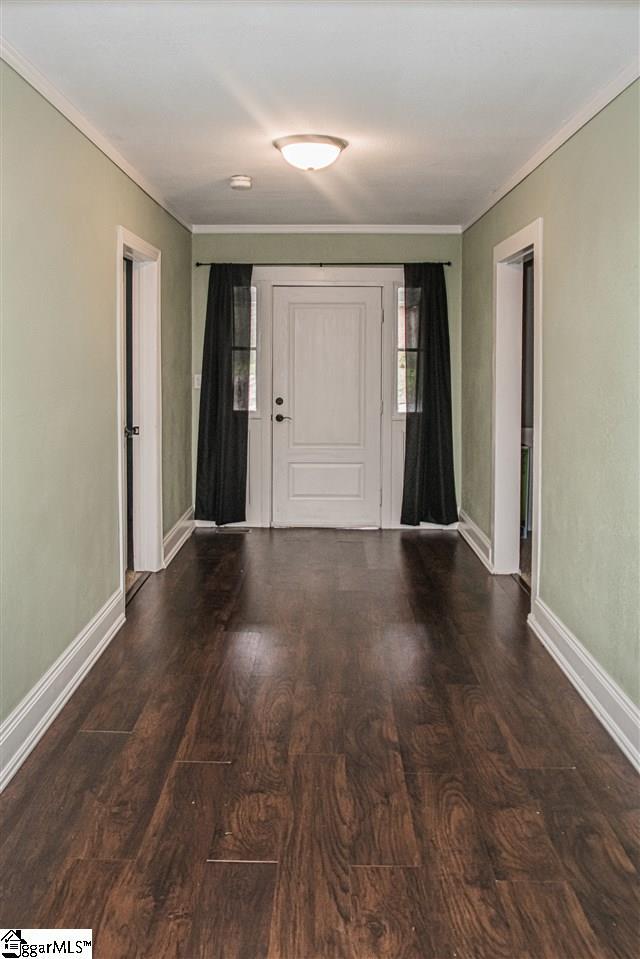 entryway with ornamental molding and dark wood-type flooring