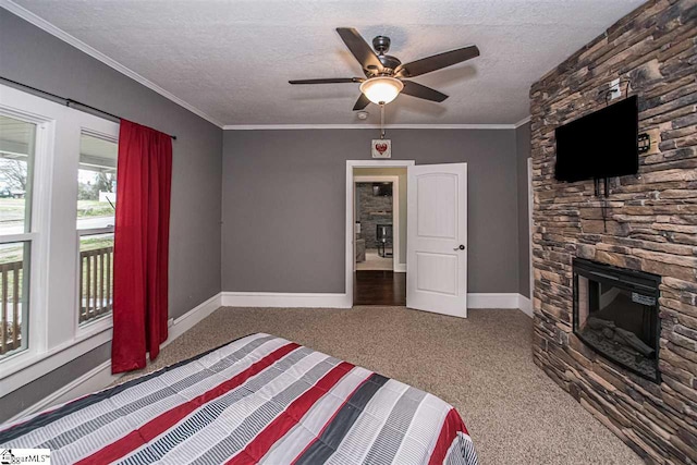 bedroom with ceiling fan, a textured ceiling, a stone fireplace, crown molding, and dark colored carpet