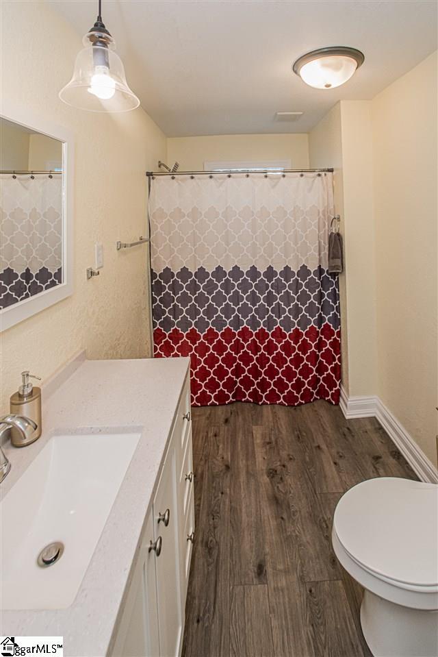 bathroom with toilet, vanity with extensive cabinet space, and hardwood / wood-style flooring