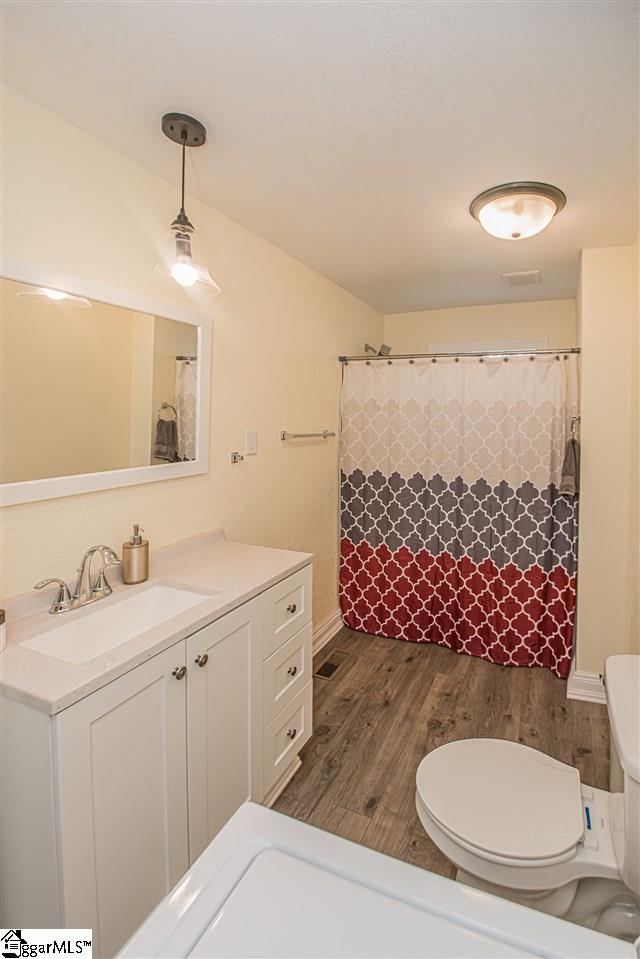 bathroom with toilet, vanity, and hardwood / wood-style floors