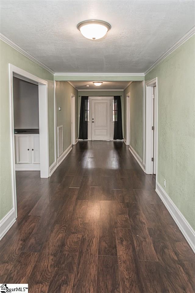 hall with crown molding, dark hardwood / wood-style floors, and a textured ceiling