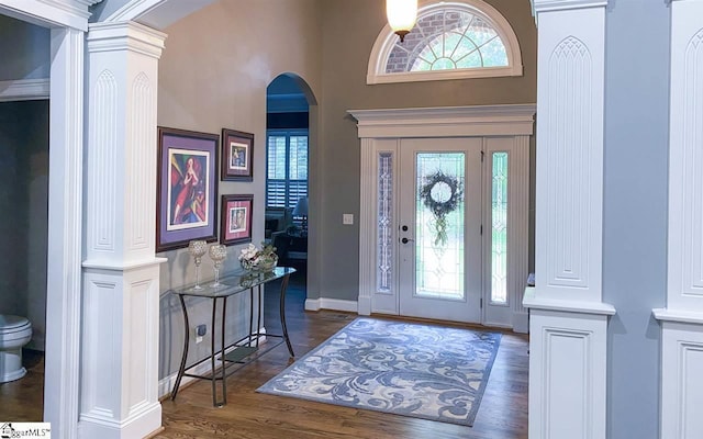 foyer featuring dark hardwood / wood-style flooring, ornate columns, and a high ceiling