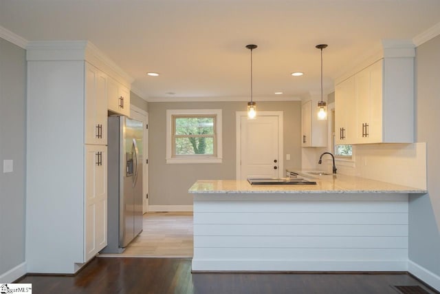 kitchen with pendant lighting, dark wood-type flooring, kitchen peninsula, stainless steel refrigerator with ice dispenser, and white cabinets