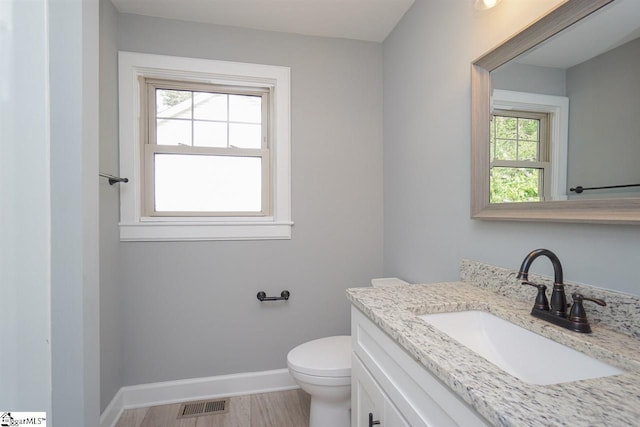 bathroom featuring oversized vanity, toilet, and plenty of natural light