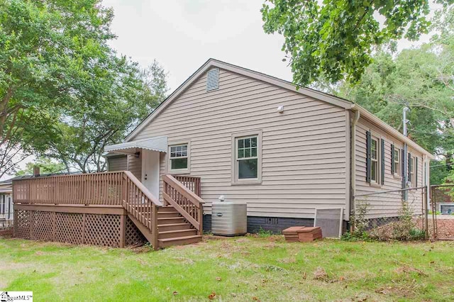 back of house with central AC unit, a wooden deck, and a yard