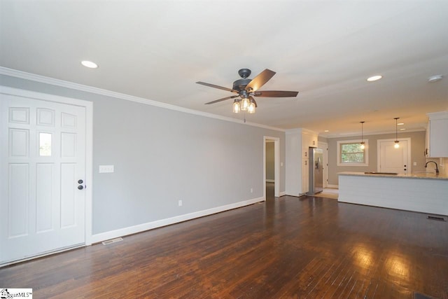 unfurnished living room featuring dark hardwood / wood-style floors, ornamental molding, ceiling fan, and sink