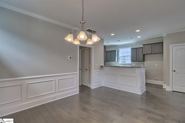 kitchen featuring pendant lighting, light stone countertops, ornamental molding, dark wood-type flooring, and an inviting chandelier