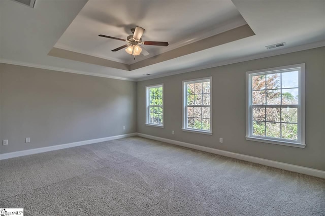 empty room featuring ceiling fan, ornamental molding, a tray ceiling, and light colored carpet