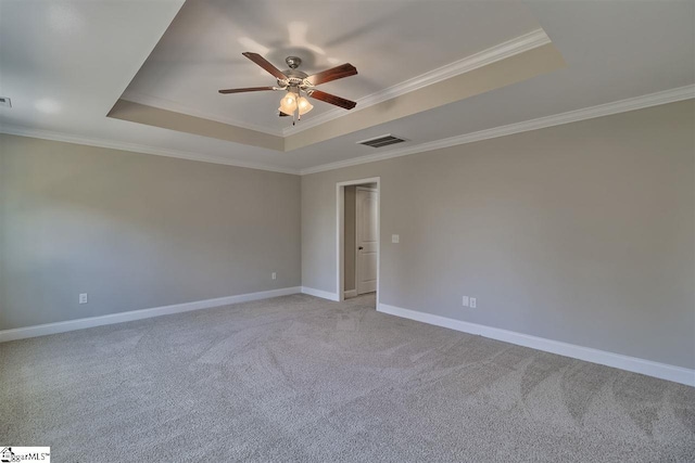 spare room featuring a raised ceiling, ornamental molding, light colored carpet, and ceiling fan