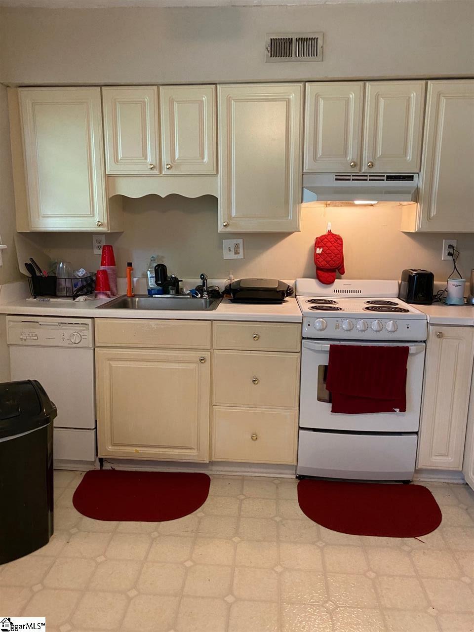 kitchen featuring white appliances, sink, and light tile flooring