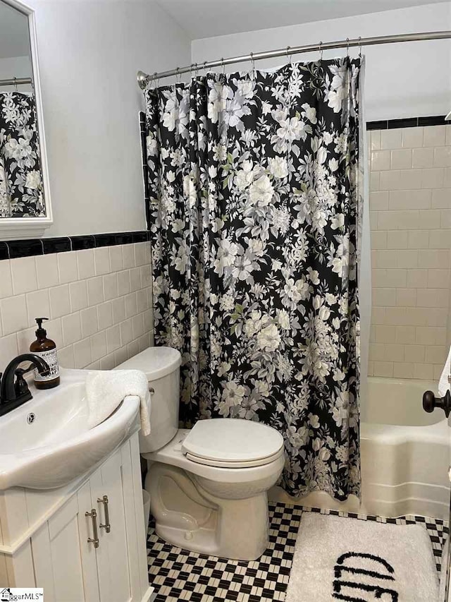 full bathroom featuring toilet, large vanity, tile walls, backsplash, and shower / tub combo with curtain