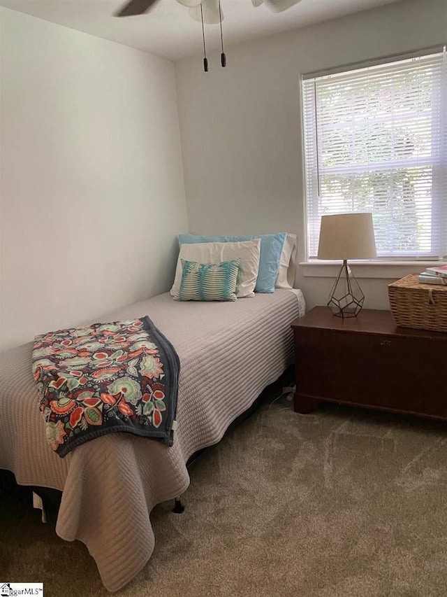 bedroom featuring multiple windows, dark carpet, and ceiling fan