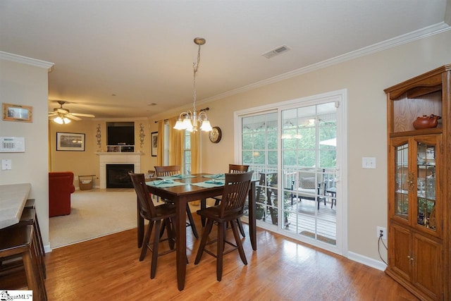 carpeted dining space featuring crown molding and ceiling fan with notable chandelier