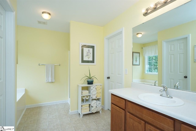 bathroom with a tub, tile flooring, and vanity