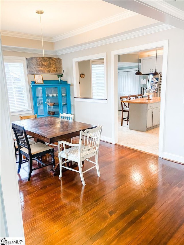 dining space featuring ornamental molding and light wood-type flooring