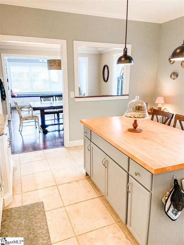 kitchen with wood counters, light hardwood / wood-style floors, decorative light fixtures, a kitchen island, and ornamental molding