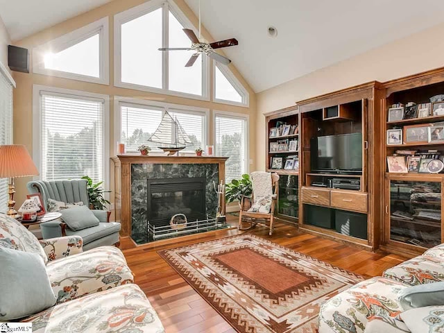 living room with a premium fireplace, high vaulted ceiling, ceiling fan, and hardwood / wood-style flooring