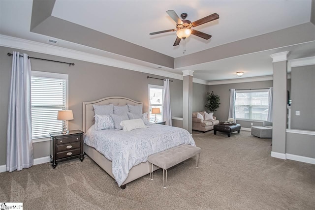 carpeted bedroom with ceiling fan, crown molding, a tray ceiling, and ornate columns