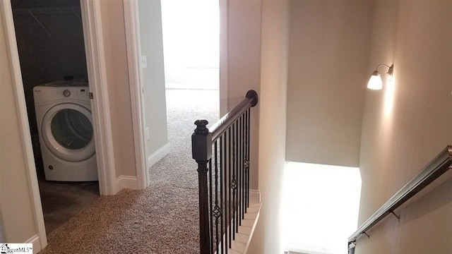 corridor with washer / dryer and dark colored carpet