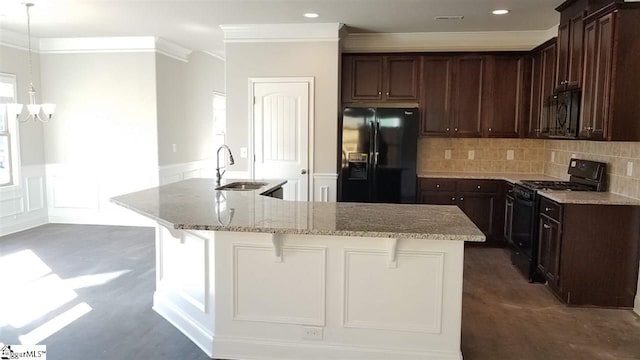 kitchen with an island with sink, sink, backsplash, light stone countertops, and black appliances