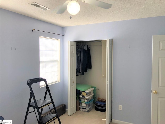 interior space featuring multiple windows, a textured ceiling, ceiling fan, and a closet