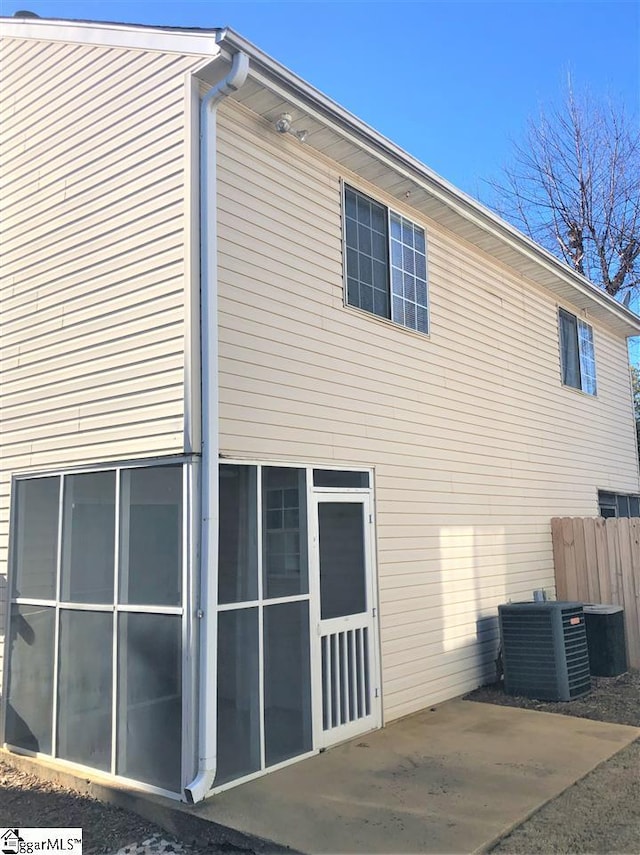 view of property exterior with a sunroom, central AC unit, and a patio area