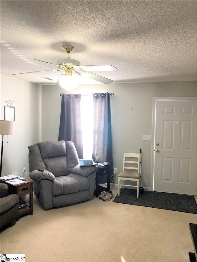 living room featuring ceiling fan, a textured ceiling, and carpet