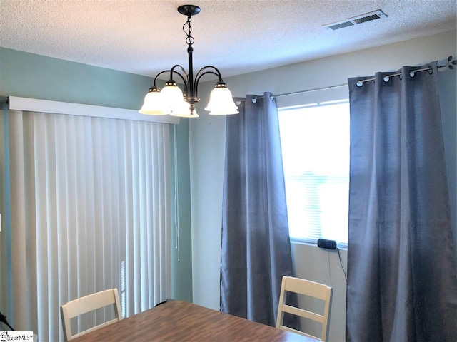 dining space with a chandelier and a textured ceiling