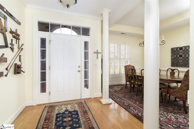 foyer entrance with ornamental molding, ornate columns, and light hardwood / wood-style flooring