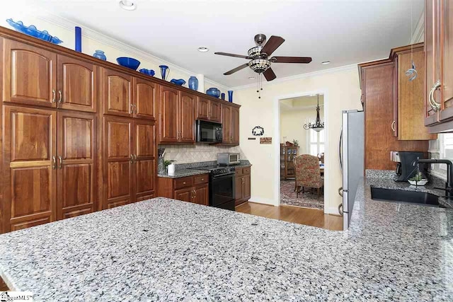 kitchen featuring ceiling fan with notable chandelier, black appliances, sink, light hardwood / wood-style flooring, and tasteful backsplash