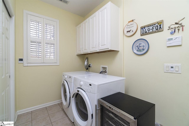 clothes washing area featuring light tile floors, electric dryer hookup, washer hookup, cabinets, and washer and clothes dryer