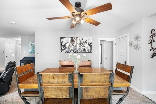 carpeted dining space with ceiling fan