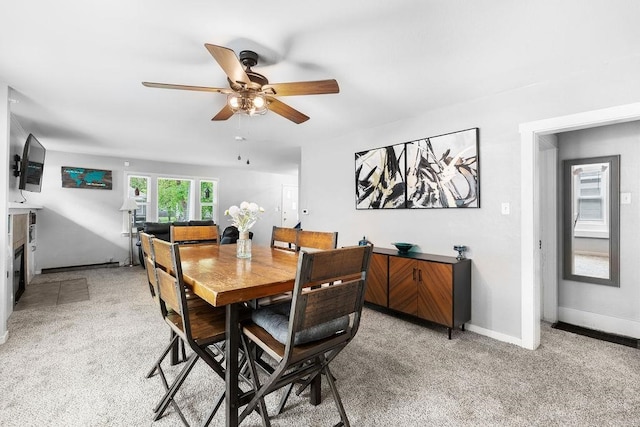 dining space with ceiling fan and light carpet