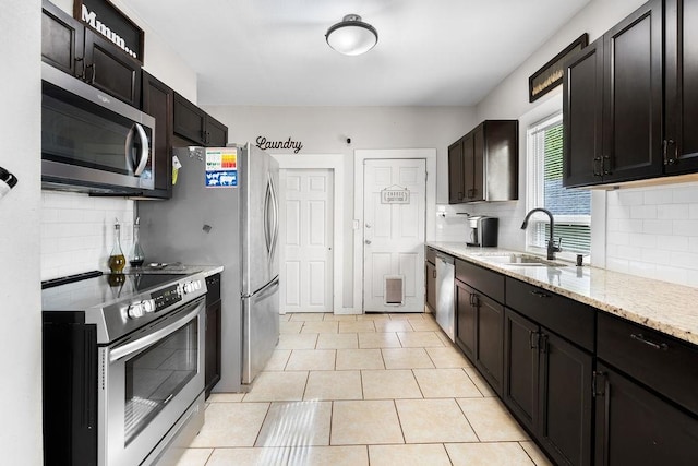 kitchen featuring backsplash, stainless steel appliances, sink, and light stone countertops