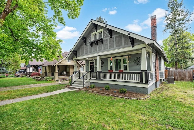 view of front of property with central air condition unit, covered porch, and a front yard