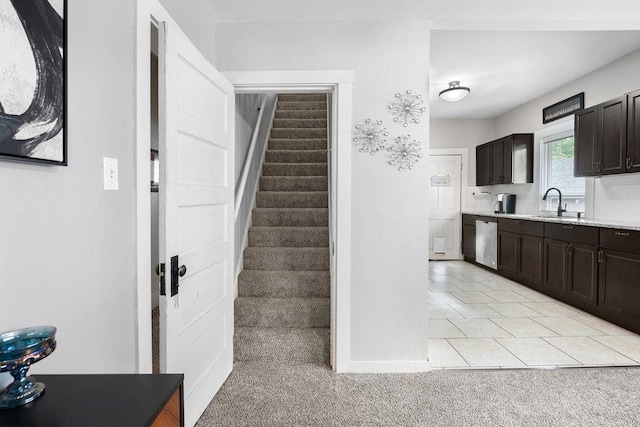 kitchen with dark brown cabinets, sink, light tile floors, and stainless steel dishwasher