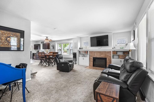 carpeted living room featuring ceiling fan and a tiled fireplace