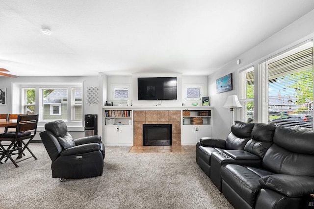 living room featuring built in features, light colored carpet, and a tiled fireplace