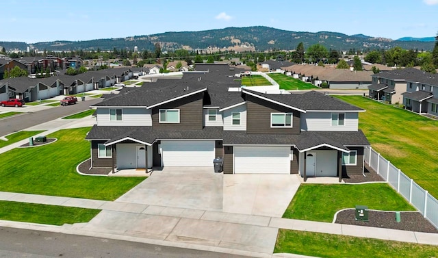 view of front facade featuring a mountain view, a front lawn, and a garage