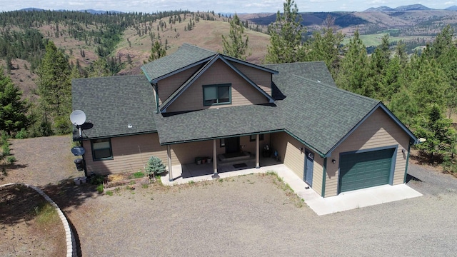 35025 Mourning Dove Ln N, Davenport, WA 99122 - view of front facade featuring roof with shingles, a mountain view, a garage, and gravel driveway